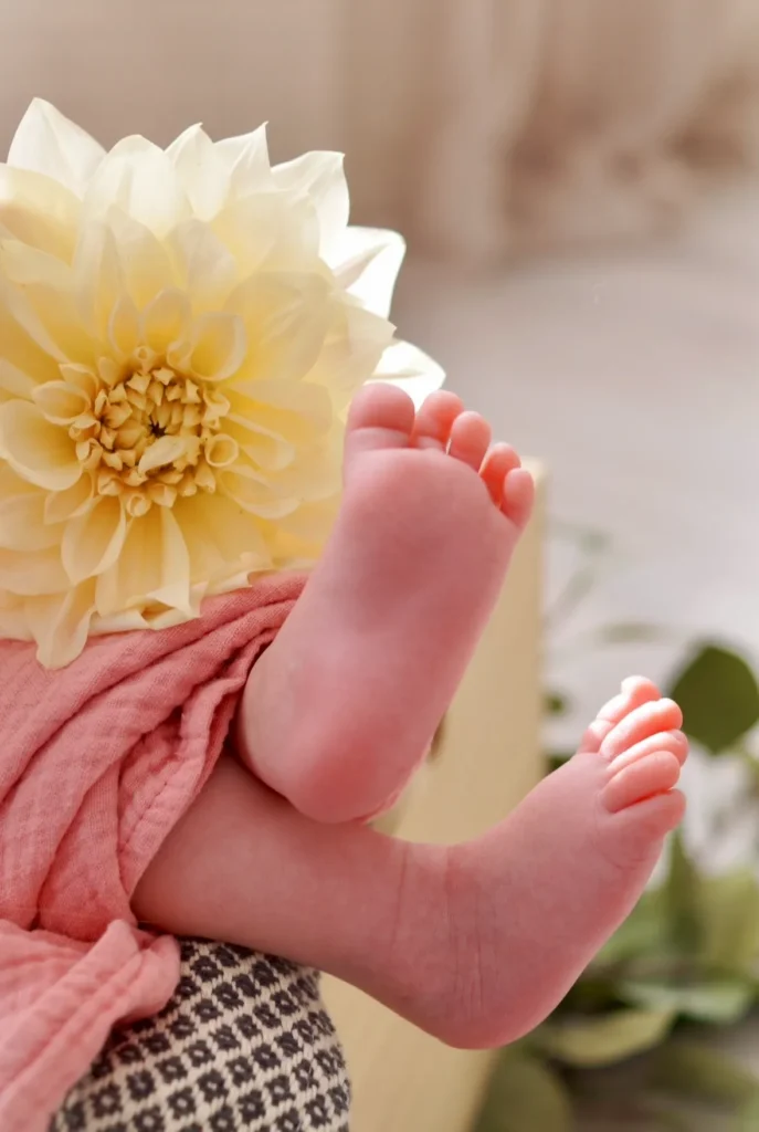 A baby's feet with a white flower on top of the baby
