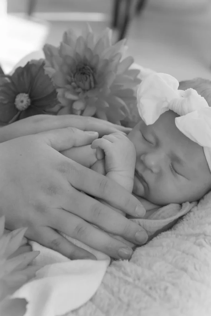A gray picture of a child sleeping with 2 flowers next to it